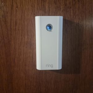 Câmara Ring Door View Cam instalada numa porta de madeira escura, com o logótipo ring visível na base